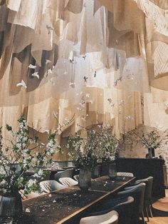 a dining room table with vases and flowers on top of it, hanging from the ceiling