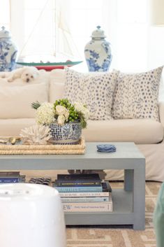 a living room filled with white furniture and blue vases on top of a coffee table