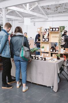 two people are standing near a table with plants on it and some boxes stacked up behind them