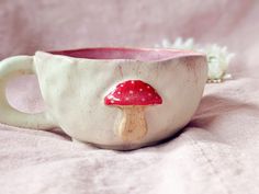 a ceramic cup with a red mushroom on it