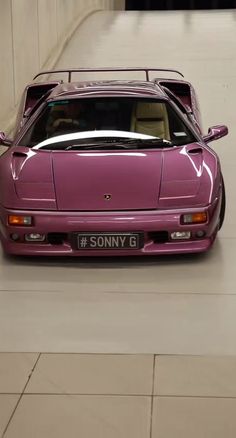 a pink sports car parked in a parking garage next to a wall with the word sony g written on it