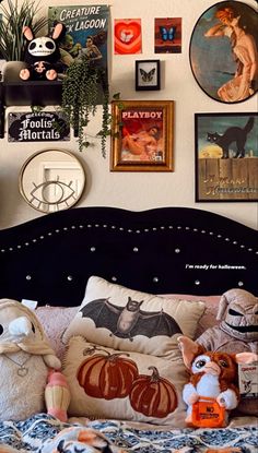 a bed topped with lots of pillows and stuffed animals next to pictures on the wall