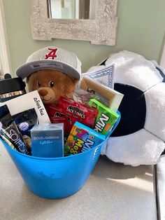 a teddy bear is sitting in a blue bowl filled with snacks and other items on the counter