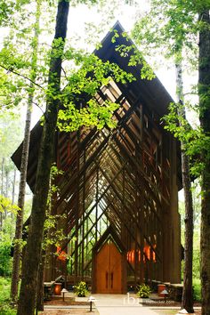 a large wooden church surrounded by trees in the woods