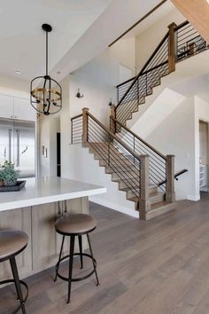 a kitchen with two stools next to a counter top and an open staircase leading up to the second floor