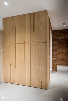 an empty room with wooden cupboards and brick wall in the backround area