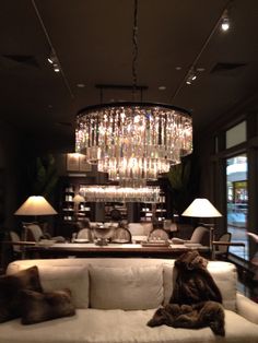 a living room filled with furniture and a chandelier hanging from the ceiling above it