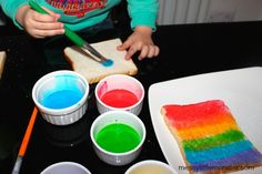 a child is painting rainbows on bread