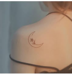 the back of a woman's shoulder with a crescent moon and spider tattoo on it