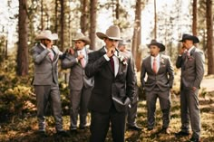 a group of men in suits and ties standing next to each other on a forest floor