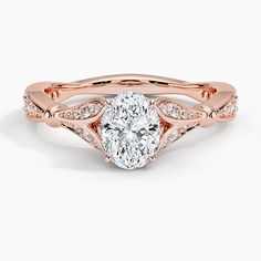 a rose gold engagement ring with an oval cut diamond in the center and side stones