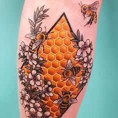 a tattoo on the leg of a woman with flowers and honeycombs around it