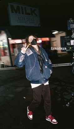 a man with dreadlocks walking down the street talking on a cell phone in front of a milk sign