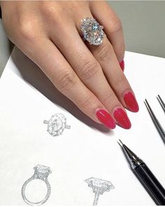 a woman's hand with red nail polish and diamond ring on top of a piece of paper