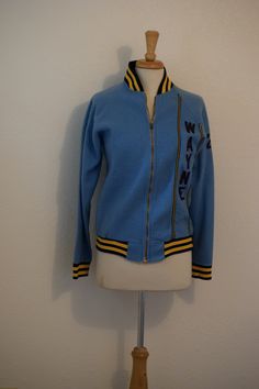 "Retro Champion for a super cool statement. Light blue nubby fleece letterman style jacket sports black and gold bands at stand up collar, cuffs and bottom band, heavy gold metal 'Talon' zipper, #20 at the left sleeve as well as small black and gold trim along with 'Wayne' appliqued vertically.  This is fun, rare and ready for a retro take on fashion. Fits like a women's small to extra small Measurements: Back of neck to bottom of jacket:  25 1/2\" Shoulder to shoulder at back:  17\" Top of sleeve to bottom of cuff:  25\" Under arm seam:  15 1/2\" Armpit to armpit:  22 1/2\" Side to side at bottom:  19\" to 21\" For a variety of vintage goodies, check out my shop @: https://www.etsy.com/shop/RagandBonesFinds For a unique pillow fashioned from my treasure trove of vintage fabric, visit my s Letterman Sweaters, Vintage Varsity Jacket, Steampunk Jacket, Unique Pillow, Stand Up Collar, Letterman Jacket, Linen Suit, Printed Shirt Dress, Vintage Champion