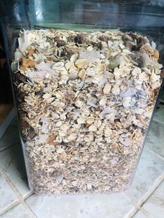 a container filled with granola sitting on top of a tiled floor