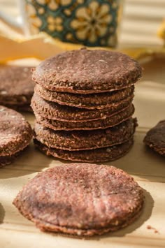 a stack of cookies sitting on top of a wooden cutting board next to a cup