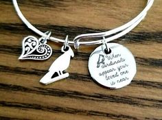 a silver bracelet with a bird on it and a heart charm hanging from the clasp