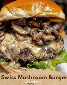 a cheeseburger with mushrooms on it sitting on top of a white plate next to a brown piece of paper