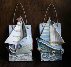 two small ceramic sailboats are hanging from strings