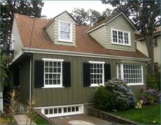 a green house with white windows and black shutters