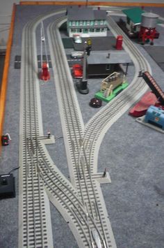 a toy train set is shown on the floor next to other model tracks and accessories