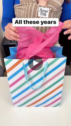 a woman holding a shopping bag with the words all these years on it in front of her face