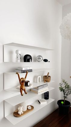 a white shelf filled with lots of books and knick knacks next to a potted plant