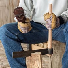 a man sitting on top of a wooden block holding a hammer