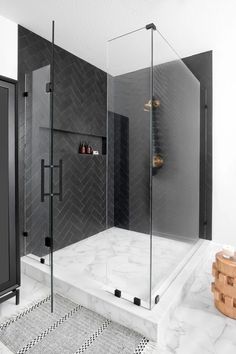 a walk in shower sitting next to a black and white tiled wall with shelves on each side