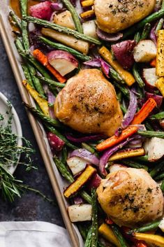 roasted chicken and vegetables on a sheet pan with serving utensils next to it