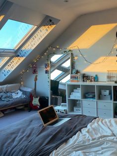 a bedroom with a laptop on the bed in front of an open window and skylights