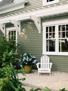 a white chair sitting on top of a brick patio next to a green building with windows