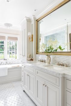 a large bathroom with white cabinets and marble counter tops