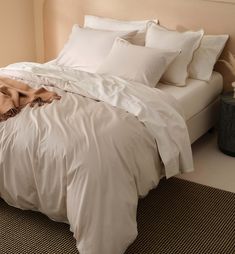 an unmade bed with white sheets and pillows