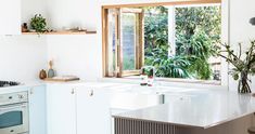 a kitchen with an oven, sink and window overlooking the trees outside in the day