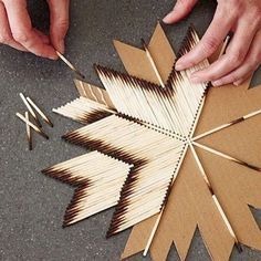 two hands are working on an ornament made out of matches and wood sticks