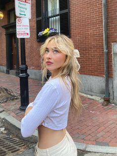 a woman standing in front of a brick building wearing a flower crown on her head