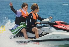 two people riding on the back of a jet ski