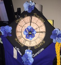 a graduation cap decorated with blue flowers and the time is 4 30 on it's side