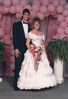 a man and woman in formal wear standing next to each other with balloons behind them