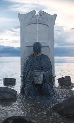 a person sitting on a chair in the water with buckets hanging from it's back