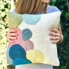 a woman holding a colorful pillow in her hands