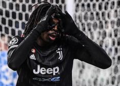 a man with dreadlocks covers his face as he stands in front of a net