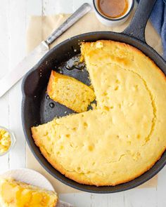 a skillet filled with cornbread next to a cup of coffee