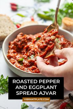 a hand holding a piece of bread over a bowl of food with the words roasted pepper and eggplant spread on it