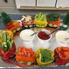 a tray filled with vegetables and dips on top of a table covered in tin foil