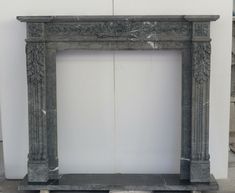 a stone fireplace with carvings on the top and sides, in front of a white wall