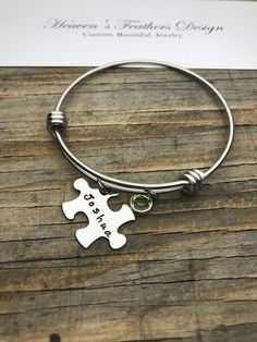 "This listing includes a stainless steel wire bangle bracelet. Each bracelet comes with one or more 1\" x 5/8\" stainless steel puzzle piece each hand stamped with a name up to 8 letters maximum and a Swarovski birthstone. Choose how many disc and birthstone sets you need with the drop down menu at checkout. One birthstone is included for each stamped disc charm. Please include in the note to seller section the name and birthstone needed for each puzzle piece. *Stainless Steel - Will not tarnish Wire Bangle Bracelets, Custom Puzzle, Horse Jewelry, Wire Bangles, Jewelry Hand, Puzzle Piece, Birthstone Gifts, Feather Design, Name Jewelry