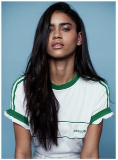 a woman with long black hair wearing a green and white shirt